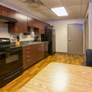 A modern kitchen with wooden cabinets, stainless steel appliances, and a hardwood floor.