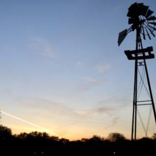 A silhouette of a windmill against a sunset sky.