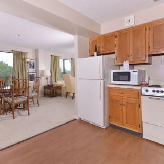 An open-layout kitchen and dining area featuring wooden cabinets, a refrigerator, stove, and microwave.