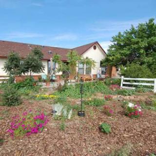 A beautiful garden surrounding a cozy home, filled with vibrant flowers and greenery.