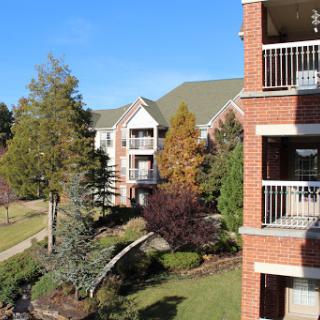 A serene view of a landscaped apartment complex under a clear blue sky.