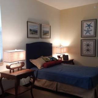 A cozy bedroom with a bed, two lamps on bedside tables, and artwork on the walls.