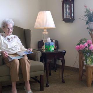 An elderly woman enjoying a quiet moment while reading in a cozy living space.
