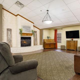 A cozy living room featuring a fireplace, piano, and television.