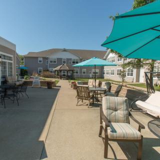 An outdoor patio area with tables, chairs, and umbrellas under a clear blue sky.
