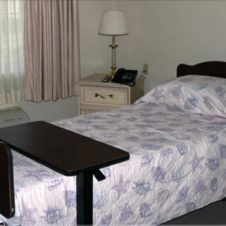 A simple hospital room with a single bed and a bedside table.