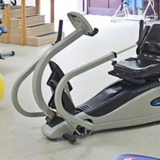 An elliptical exercise machine positioned indoors in a gym setting.