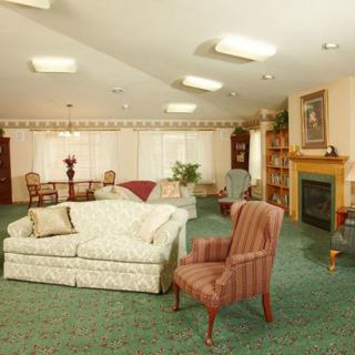 A cozy living room with a fireplace, featuring a sofa, armchair, and dining area.