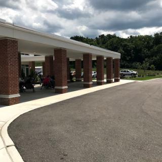 A view of a brick building with a covered entrance, set against a cloudy sky.