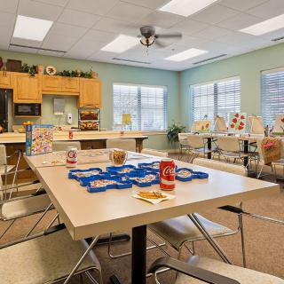 A bright classroom setting with tables, chairs, and various educational materials arranged for learning activities.