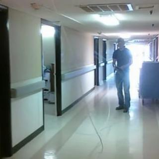 A person performing maintenance or cleaning in a hospital hallway.