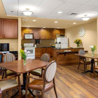A cozy kitchen and dining area with wooden tables and chairs, featuring modern appliances and warm decor.