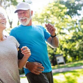 An elderly couple enjoys jogging together in the park, embracing a healthy and active lifestyle.