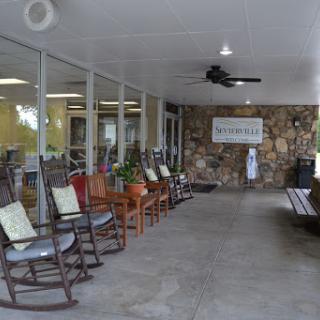 A cozy waiting area featuring rocking chairs, a stone wall, and plenty of natural light.