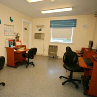 A small office space with multiple desks and chairs, equipped with computers.