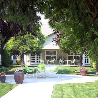 A tranquil garden setting with a house, surrounded by lush trees and a well-maintained lawn.
