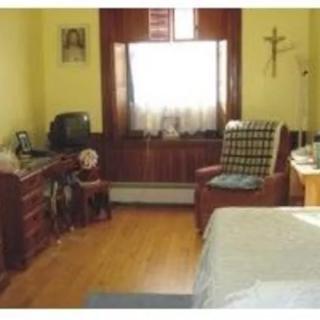 A cozy bedroom with a window, desk, chair, and bed.