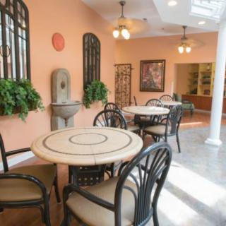A cozy cafe interior with tables and chairs, decorated with plants and warm lighting.