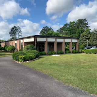 A well-maintained building surrounded by greenery and blue skies.