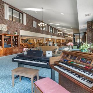 A spacious interior featuring musical instruments, comfortable seating, and bookshelves.