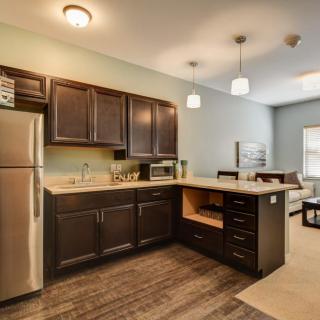 A modern kitchen with dark wood cabinets and stainless steel appliances in an open concept layout.