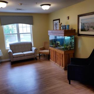 A cozy living room with seating and an aquarium by the window.