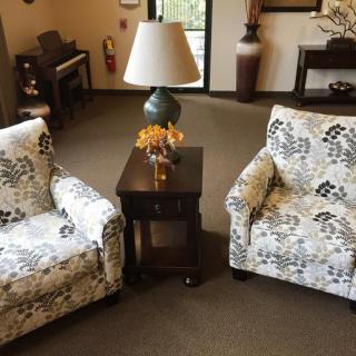 A cozy living room setting with floral-patterned chairs flanking a wooden table and lamp.