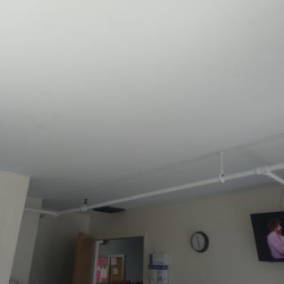 A view of a room featuring a ceiling, a wall clock, and a television.