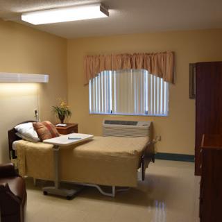 A well-lit hospital room featuring a patient bed and basic amenities for care.