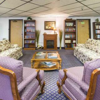 A cozy living room with sofas, armchairs, and bookshelves lining the walls.