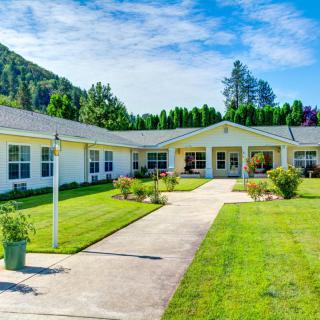 A large, single-story residential building surrounded by a well-maintained lawn and garden.