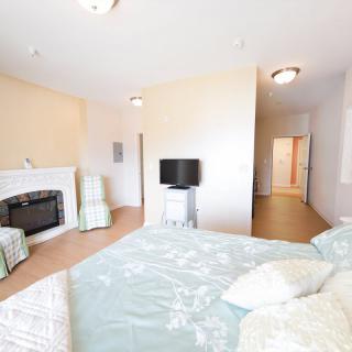 A spacious and bright bedroom featuring a cozy fireplace, a large bed, and a television.