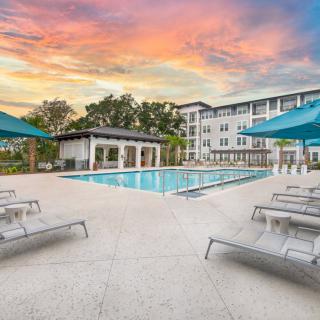 A tranquil swimming pool area at sunset, featuring lounge chairs and umbrellas, perfect for relaxation.