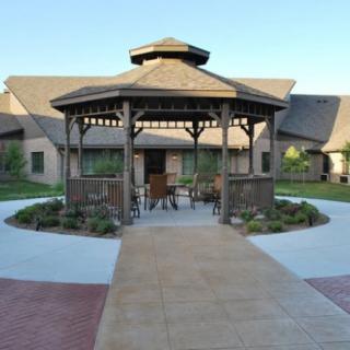 A wooden gazebo surrounded by a landscaped garden area with a paved walkway.