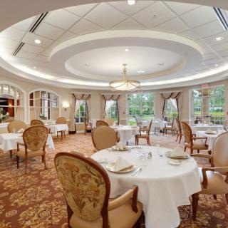 A luxurious and spacious dining room with elegant decor and round tables set for guests.