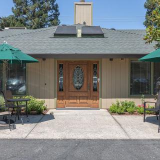 A quaint building entrance with outdoor seating and green umbrellas.