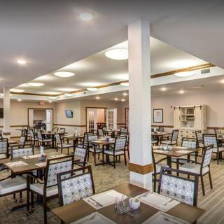 A spacious dining area with neatly arranged tables and chairs, well-lit by overhead lights.