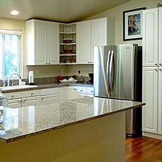 A modern kitchen with white cabinets and a granite countertop.
