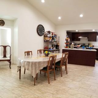 A spacious open-plan dining area with a table, chairs, and a view into the kitchen.
