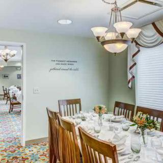 A formal dining room with a set table and elegant chandelier lighting.