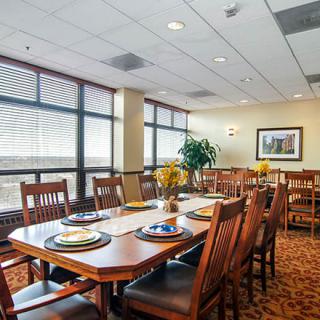 A spacious dining room with a large table, surrounded by wooden chairs and decorated with modern furnishings.