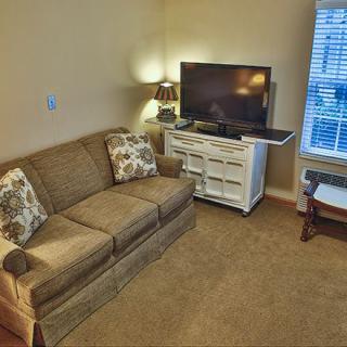 A cozy living room with a sofa, TV, and a window letting in natural light.