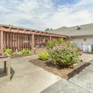 A well-maintained backyard garden with a patio area and various plants.