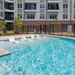 An outdoor swimming pool located within an apartment complex.