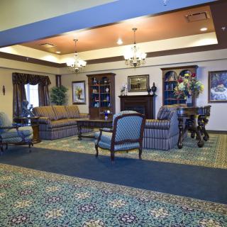 A well-furnished lobby featuring a seating area with sofas and chairs, decorative lighting, and detailed carpeting.