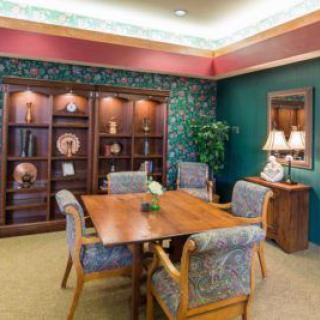 A cozy meeting room with wooden furniture, decorative bookshelves, and an indoor plant.