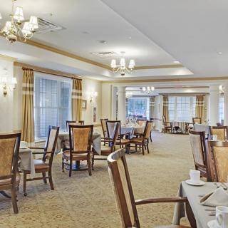 An elegant dining room with neatly arranged tables and chairs, adorned with classic lighting fixtures.