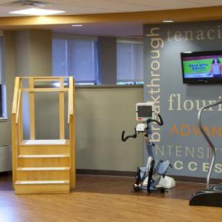 A modern rehabilitation facility featuring exercise equipment including a stationary bike and treadmill, along with wooden stairs for therapy exercises.