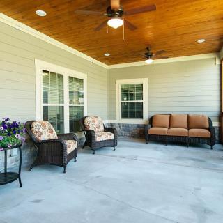 A cozy covered patio with comfortable seating and ceiling fans.