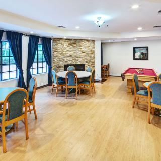A cozy common room with tables, chairs, and a pool table.